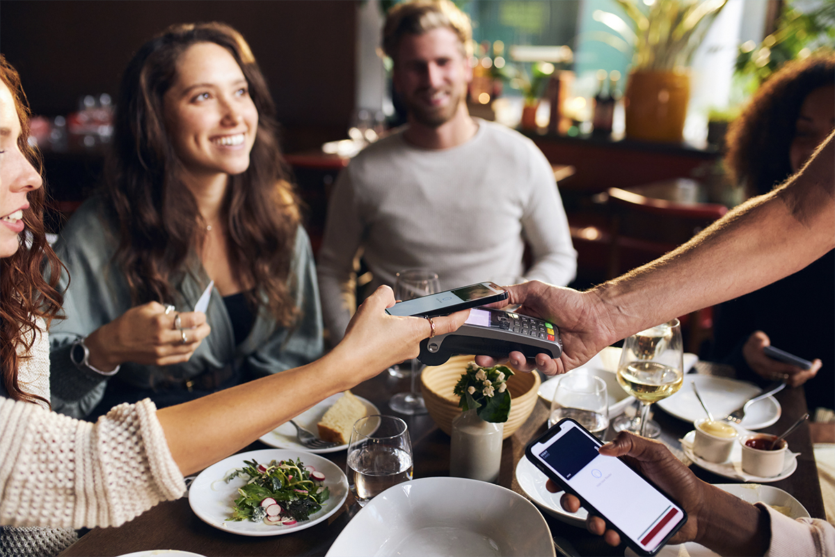 A group of people paying for their dinner with mobile banking.