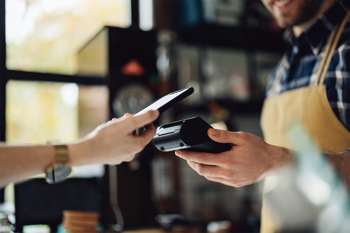 A person using their mobile device to pay at the cafe.