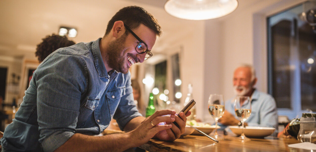 A man checking his mobile phone at the dinner table.