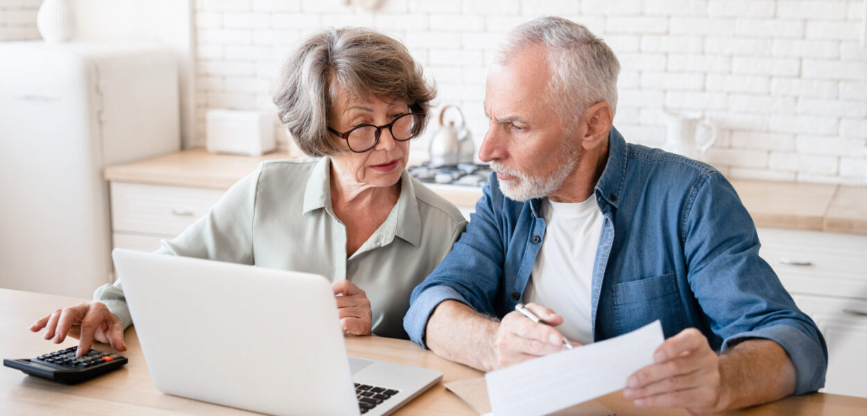 Busy caucasian old couple making calculations at home kitchen Busy caucasian old elderly senior couple making calculations at home kitchen, checking the document, revising data, information, counting domestic bills and rentals