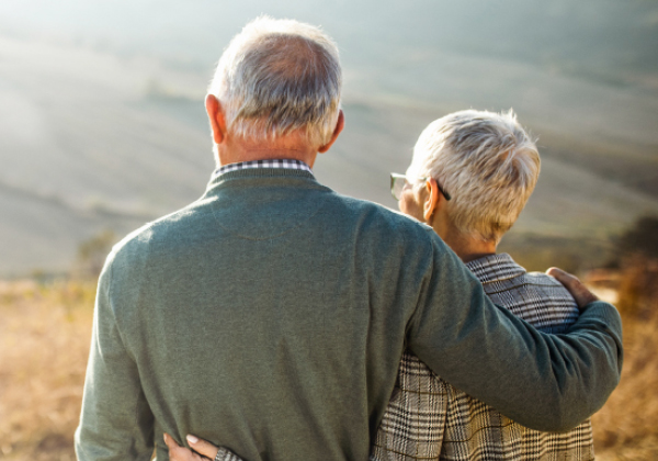 A older couple staring off into the hills while the sun is setting.