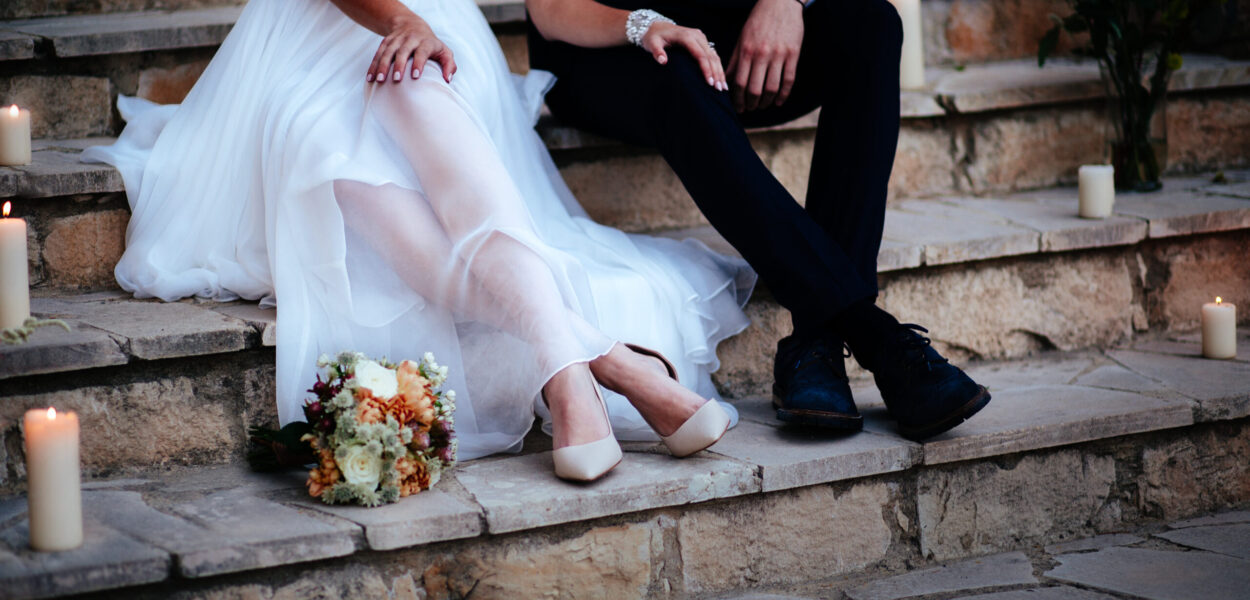 Close-up of newlywed couple's feet sitting on stone stairs and relaxing at wedding reception