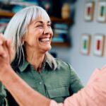 Carefree man in his 50s and woman in her 60s dancing, woman smiling towards man