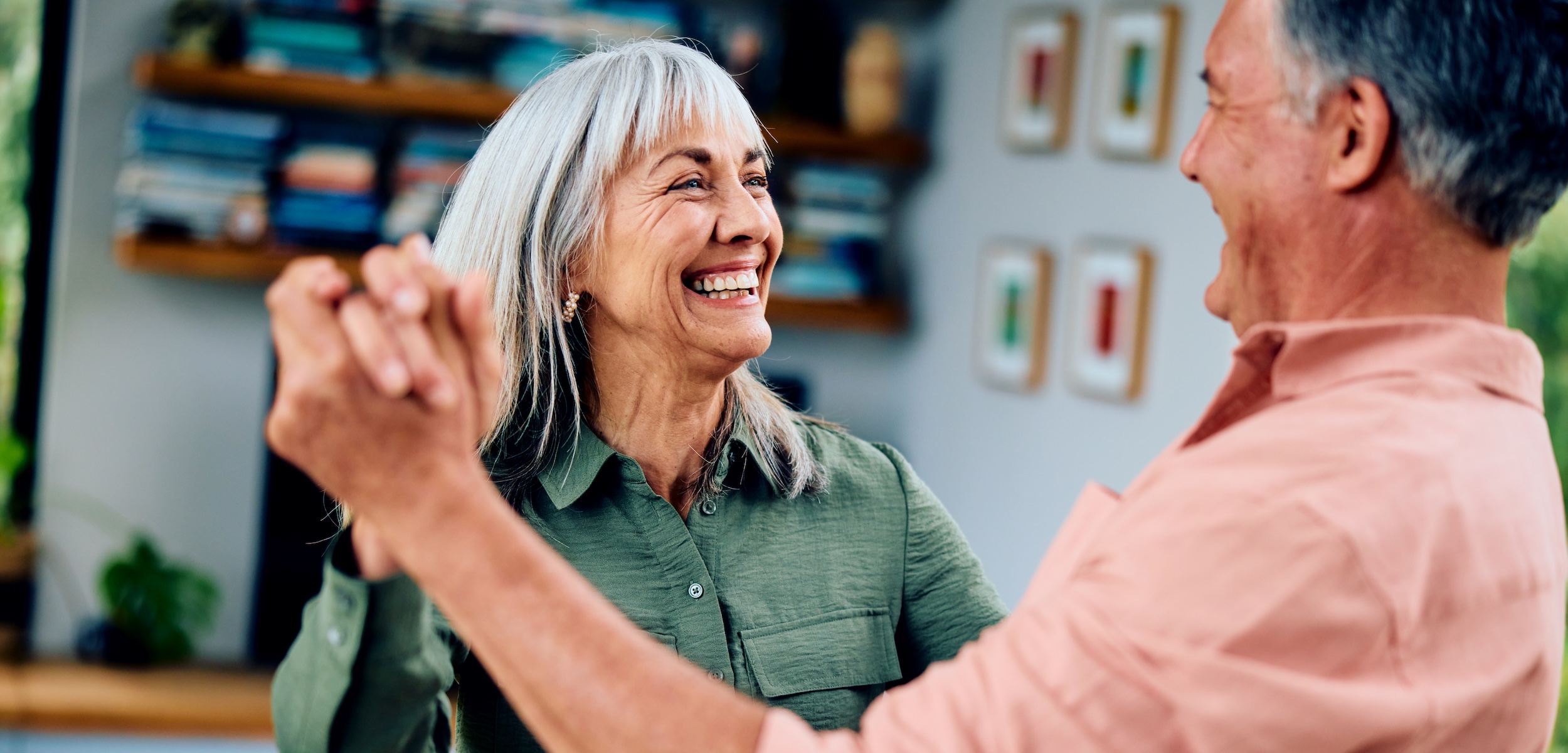 Carefree man in his 50s and woman in her 60s dancing, woman smiling towards man
