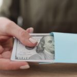 Female hands get a pack of dollars from an envelope