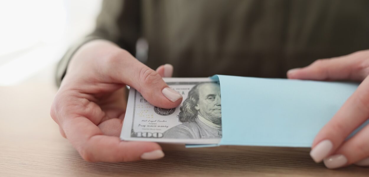 GettyImages-1529827670.resized Female hands get a pack of dollars from an envelope